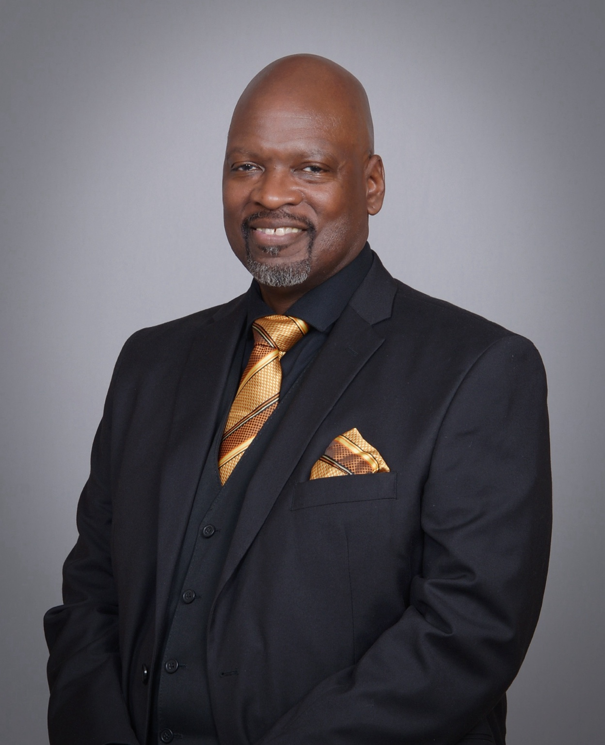 Phillip O. Hanks in a black suit with a gold tie